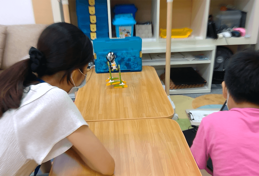 先生と一緒にロボットを作っている教室風景